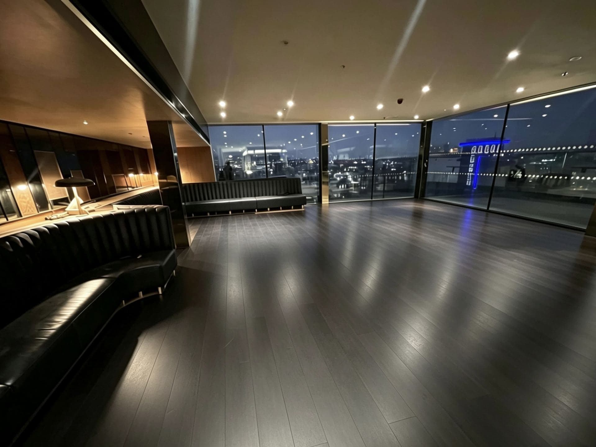 Penthouse lounge and bar fit-out by Avex with dark timber flooring and London skyline views